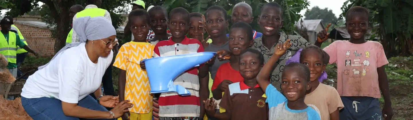 Groupe d'enfants souriants en Guinée tenant une cuvette de toilettes bleue SATO